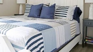 A bedroom with a bed, a ceiling fan, a nightstand, a lamp, and a framed picture on the wall. - Gulf Coast Condos on the Sand Dunes - 202 (Dauphin Island)