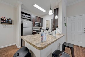 A modern kitchen with granite countertops, stainless steel appliances, and pendant lighting.