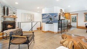 Una sala de estar moderna con chimenea, un televisor de pantalla plana grande y un comedor con mobiliario de madera.