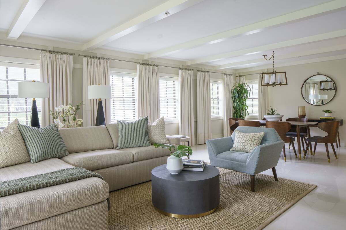 A modern living room with a sofa, armchairs, a coffee table, and a dining area with a table and chairs.