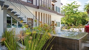 Un edificio moderno con una scala, un elemento d'acqua e un giardino con diverse piante.