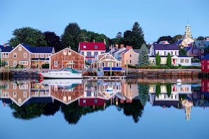 A waterfront town with a variety of buildings, including a prominent wooden structure and a church with a steeple. - Marshview (Hampton)
