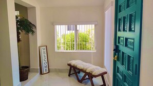 A room with a bench, a welcome sign, a window with bars, and a green door with decorative panels. - Beautiful Chic Home Near Coconut Grove & Brickell (Miami)