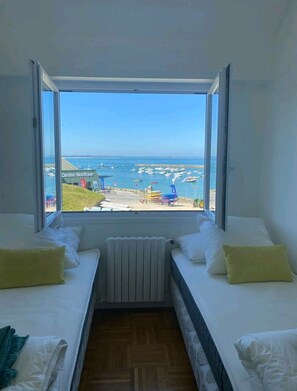 Une chambre avec deux lits, vue sur la mer, et une enseigne indiquant le « Centre Nautique ».