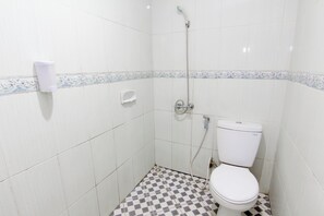 Un baño pequeño con azulejos, un inodoro, una ducha y un dispensador de jabón.