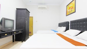 Una habitación de hotel con cama, escritorio con televisor, armario y equipo de aire acondicionado.