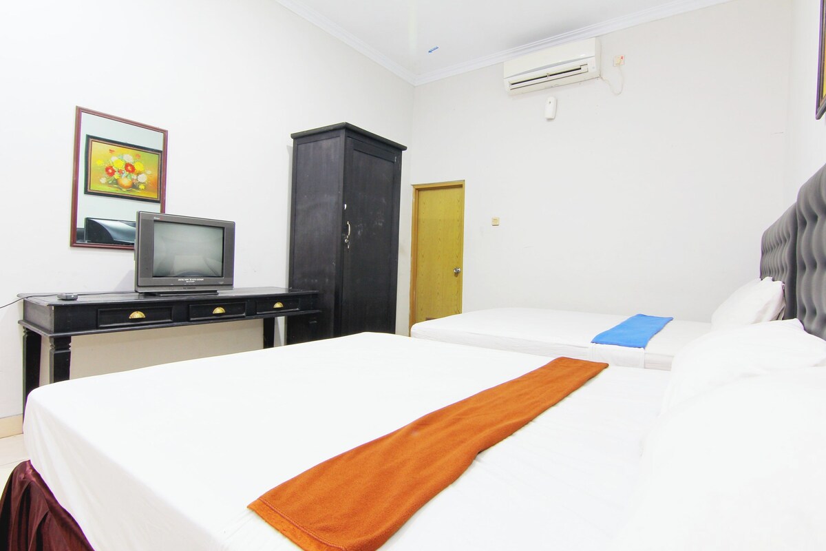 Una habitación de hotel con cama, un escritorio con televisor, un armario y una puerta.