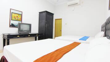 A hotel room with a bed, a desk with a television, a wardrobe, and a door.
