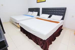 Habitación de hotel con dos camas, cada una con cabecera y ropa de cama blanca.