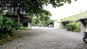 Un patio empedrado con baldosas hexagonales, rodeado de edificios verdes y plantas en macetas.