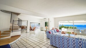 A spacious living area with a staircase, a sofa set, and a view of the ocean.