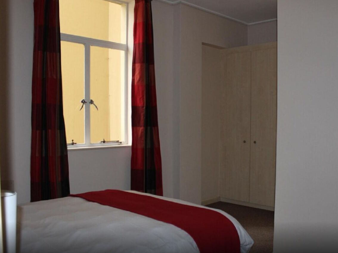 A room with a bed, a wardrobe, and a window with curtains.