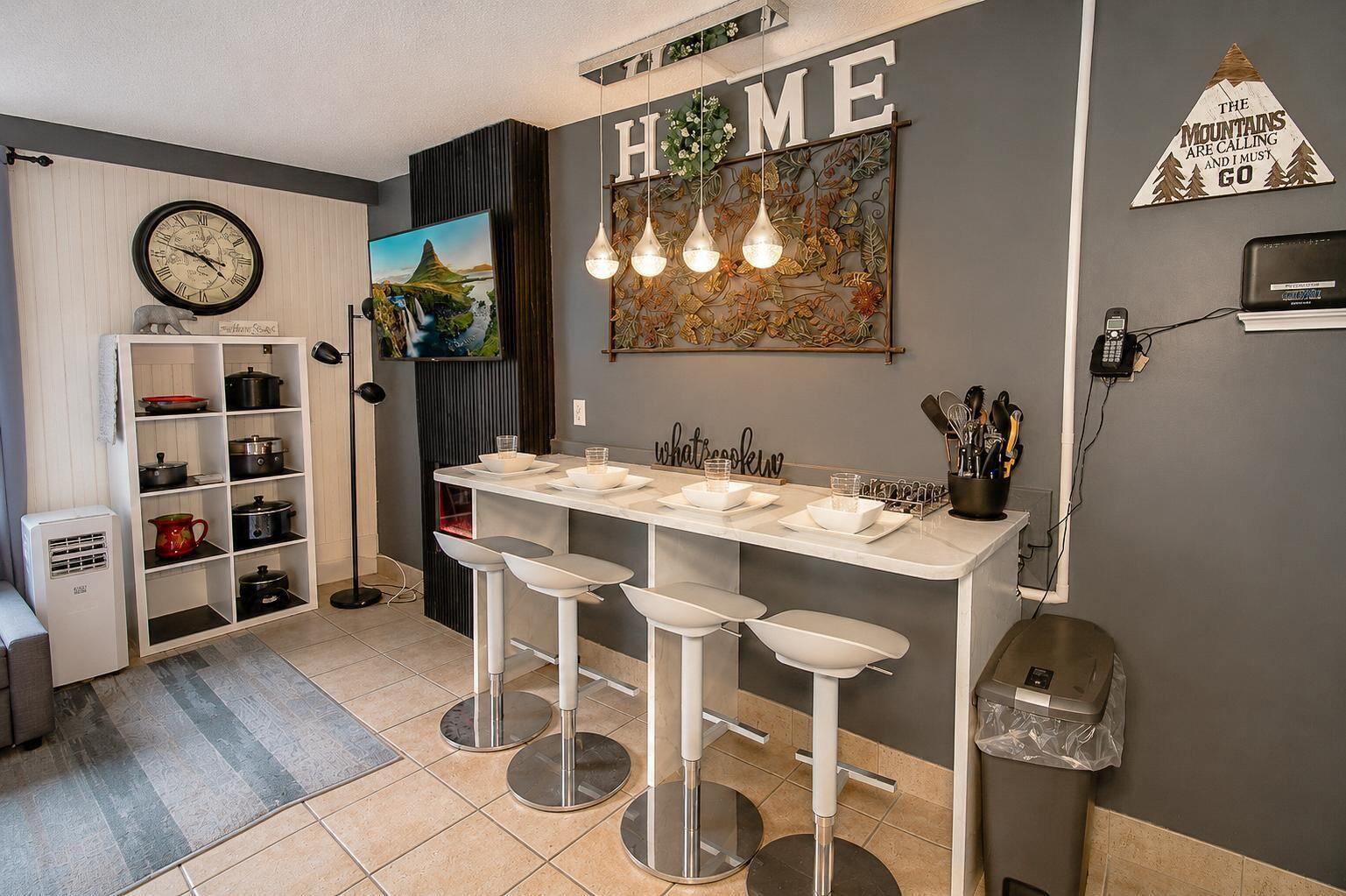 A modern kitchen with a bar area, a clock, and a decorative wall sign.