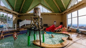 An indoor swimming pool with a water slide, a wooden structure, and a view of the outdoors. - SC 2211: Chic Mountain Studio | Perfect for Summer Adventures (Snowshoe)