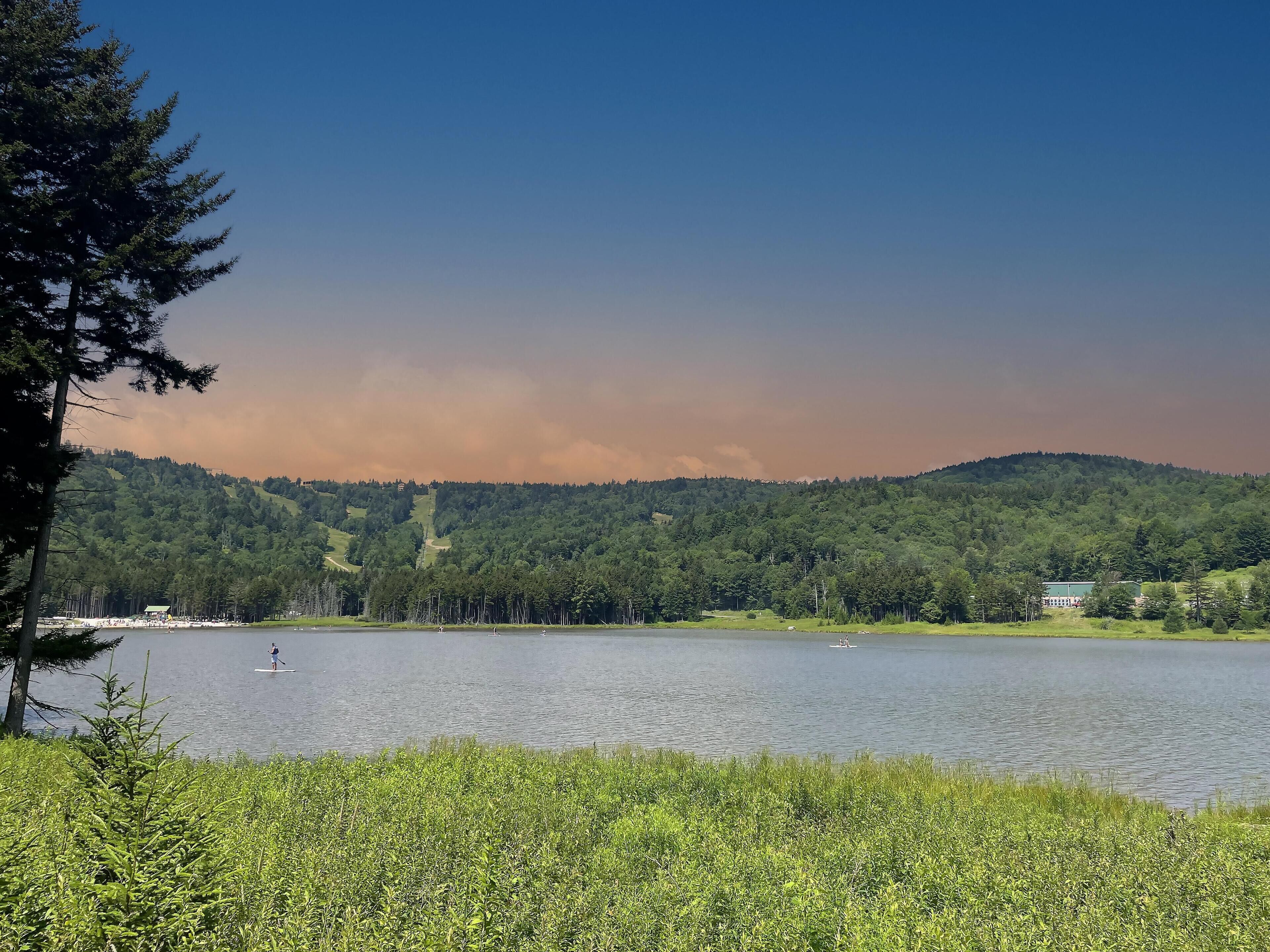A lake with a forested hill in the background.