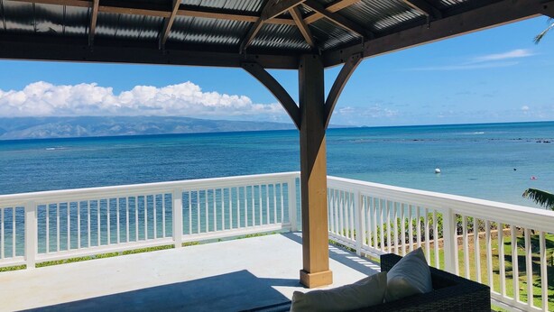 A covered outdoor area with a view of the ocean and distant mountains.