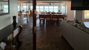 A spacious living area with a dining table and chairs, a sofa, and a ceiling fan.
