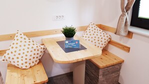 Um espaço de estar acolhedor com uma pequena mesa, uma planta em vaso e uma almofada estampada em bolinhas.