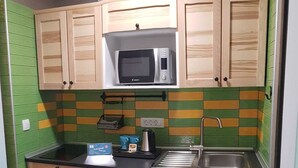 Uma cozinha compacta com armários de madeira, micro-ondas, pia e cafeteira.