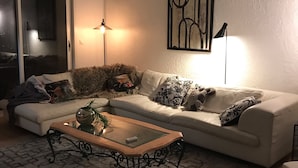 A living room with a sofa, coffee table, and decorative pillows. There is a lamp and a painting on the wall. - Villa 5 Chambres, vue Mer, Piscine, 5´ des Plages et Golf, Terrasses, Parking (Mandelieu-la-Napoule)