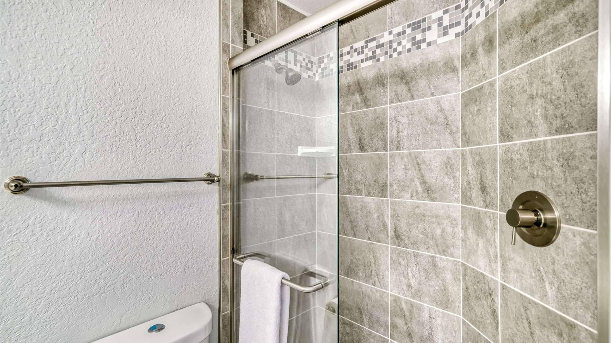 A bathroom with a glass shower enclosure, a towel rack, and a toilet.