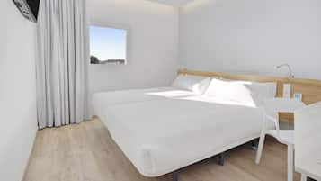 A modern hotel room with a large bed, a bedside table, a chair, and a window with a view.