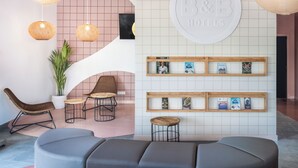 Zona de recepción de hotel con diseño moderno, que incluye un mostrador de recepción, un área de descanso y una pared con el letrero de B&B Hotels.