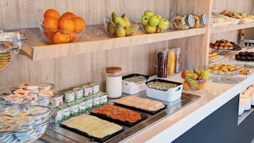 A buffet with various food items including fruits, pastries, and dairy products.