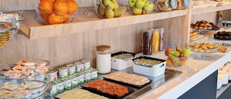 A buffet with various food items including fruits, pastries, and dairy products.