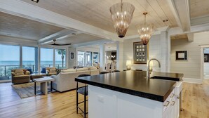 A spacious living area with a large island, a kitchen with a black countertop, and a view of the ocean. - 95 Dune Lane -Oceanfront | Island Oasis | Booking now for 2027! (Hilton Head Island)