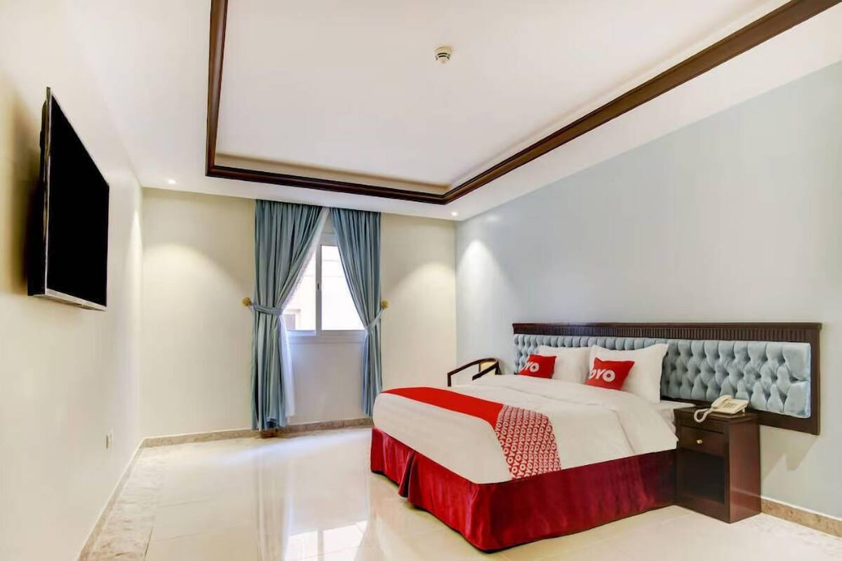 Une chambre d’hôtel avec un grand lit, une table de chevet avec un téléphone et un téléviseur à écran plat fixé au mur.