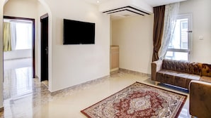 Amplia sala de estar con televisor de pantalla plana, un sofá, un tapete estampado y piso de mármol.
