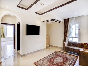 A spacious living area with a flat-screen TV, a sofa, a patterned rug, and a marble floor. - Al Tamayoz Al Raqi Al Salamah (Jeddah)
