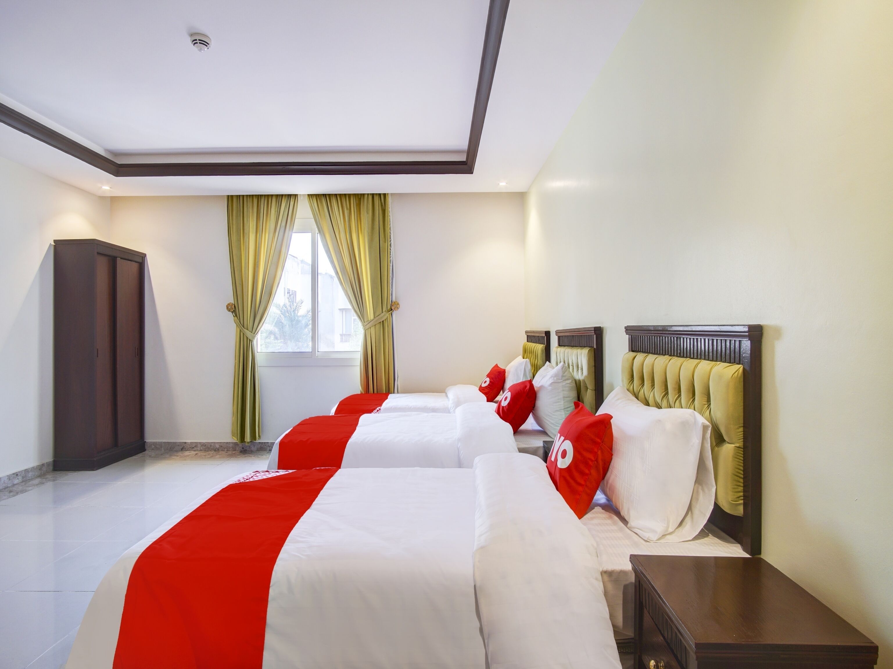 Una habitación de hotel con una cama grande, un armario y una ventana con cortinas.