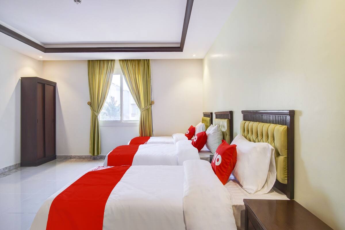 Une chambre d’hôtel avec un grand lit, une armoire et une fenêtre avec des rideaux.