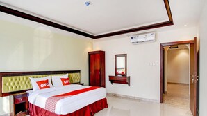 Habitación de hotel con una cama grande, un armario, un espejo y una puerta que da a otra habitación.