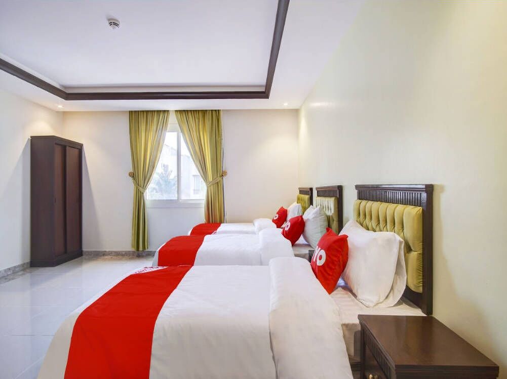 Una habitación de hotel con una cama grande, una mesita de noche, un armario y una ventana con cortinas.