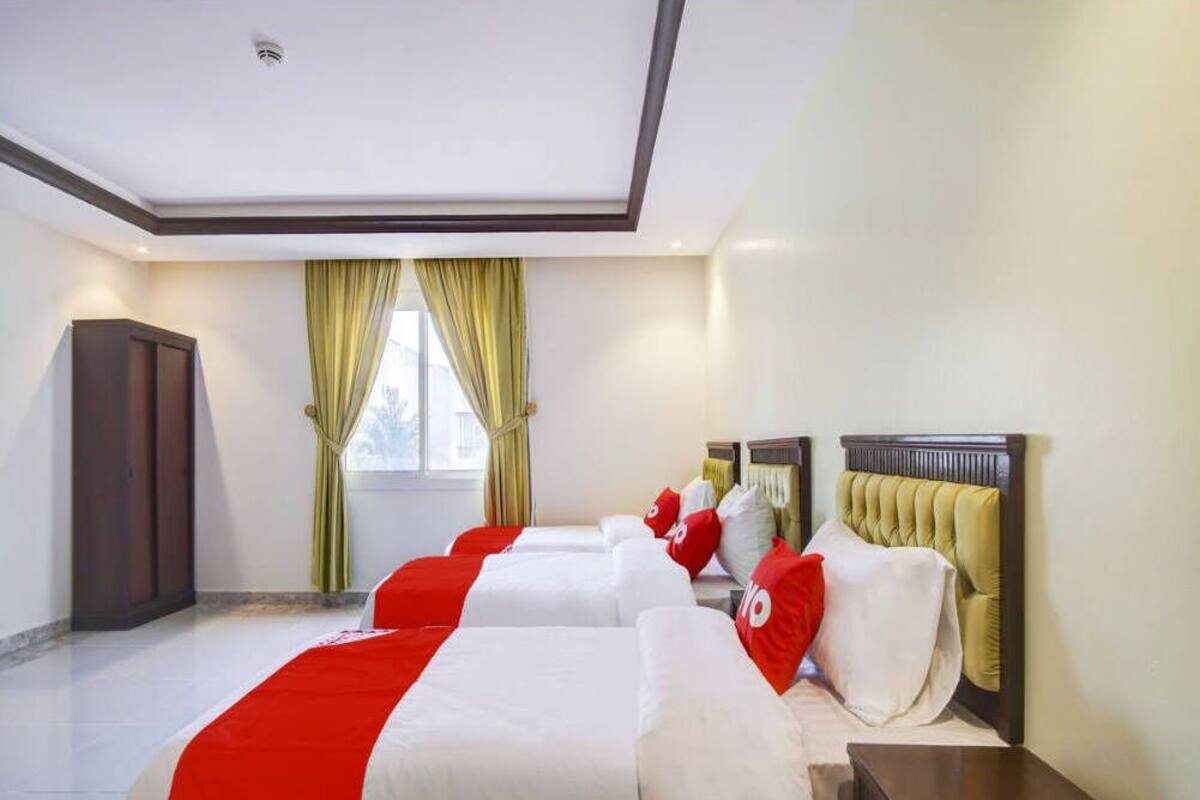 Une chambre d’hôtel avec un grand lit, une table de chevet, une armoire et une fenêtre avec des rideaux.