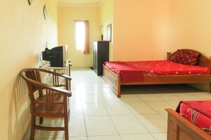 Un dormitorio con una cama, una silla de madera, un escritorio con televisor y un armario.