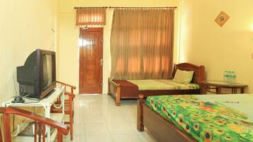 A hotel room with a bed, a wooden chair, a small table, a television, and a door.