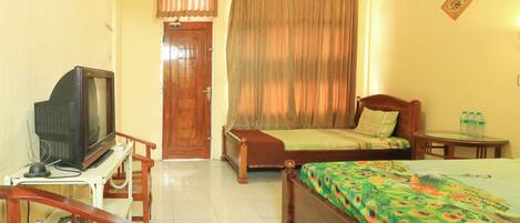 A hotel room with a bed, a wooden chair, a small table, a television, and a door.