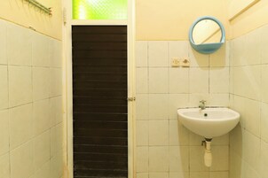 Un baño con paredes de azulejos blancos, un lavamanos blanco y un espejo.