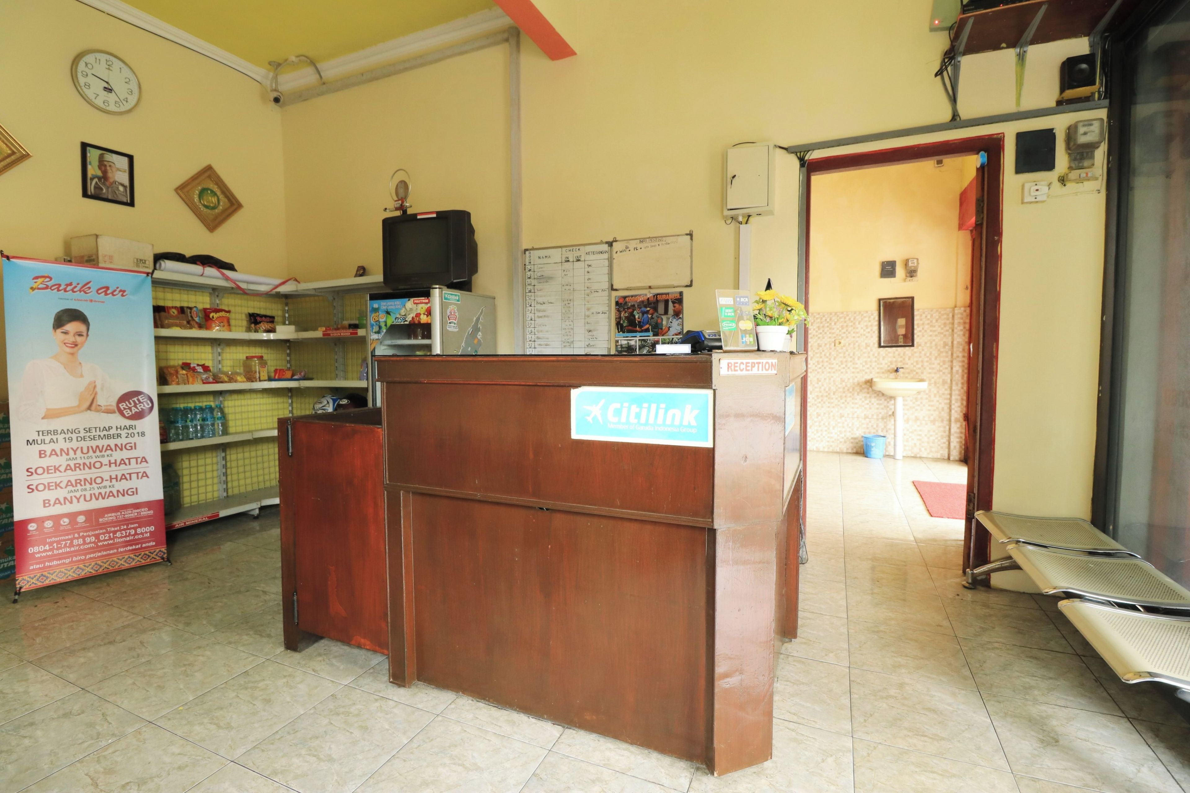 A reception desk with a sign, a clock, and a counter with various items.
