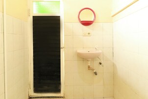 A bathroom with a white tiled wall, a black door, a pink sink with a mirror above it, and a white toilet.