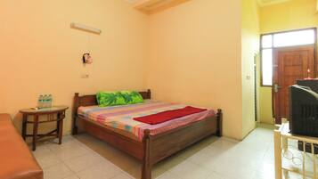 A bedroom with a bed, a small table, a chair, a television, and a door.