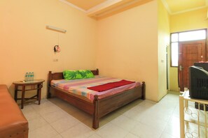 Una camera da letto con un letto, un tavolino, una sedia, una televisione e una porta.