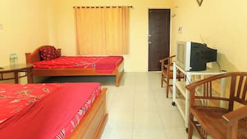 A hotel room with two beds, a television on a stand, a chair, and a door.