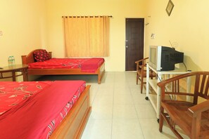 A hotel room with two beds, a television on a stand, a chair, and a door. - Penginapan Pondok Rizqi Syariah by Zuzu (Sidoarjo)