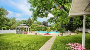Ein Garten mit Schwimmbad, Pavillon und gepflegtem Rasen.