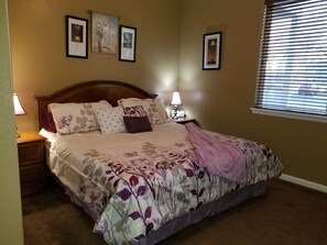 A neatly made bed with floral bedding, two bedside lamps, and framed pictures on the wall.